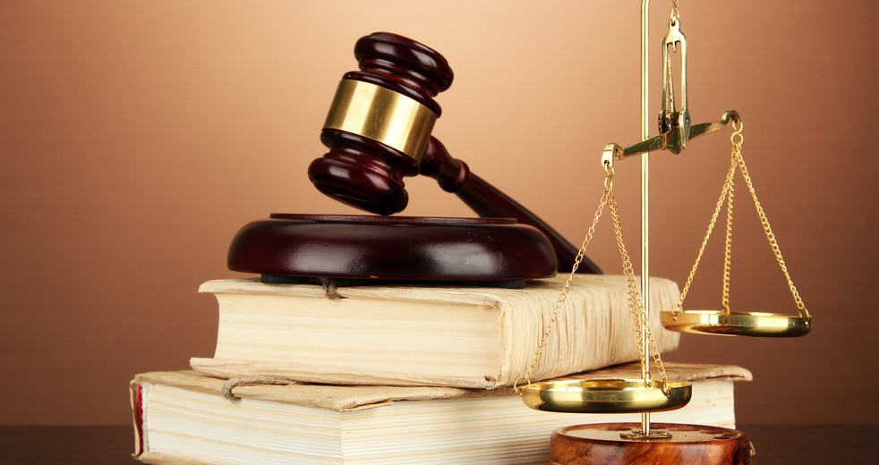 Golden scales of justice, gavel and books on brown background